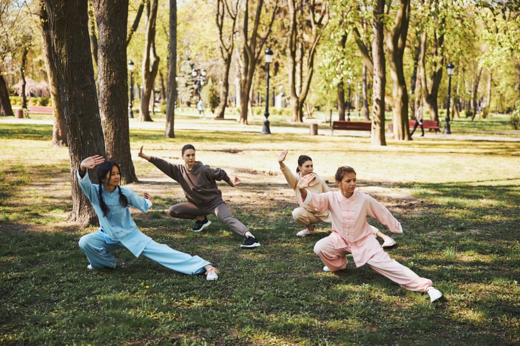 Tai chi practitioners standing in snake creeps down pose